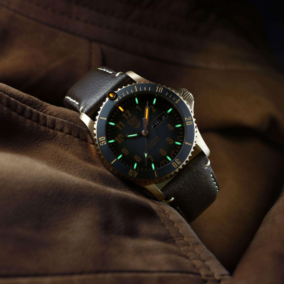 Men's automatic watch on leather surface with green luminous hands and black leather strap