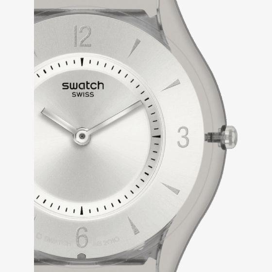 Silver watch dial close-up with Swatch logo, stick hands, and minute track.