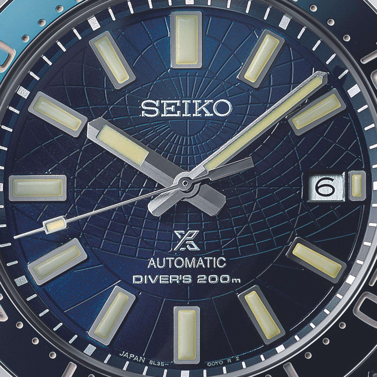 Close-up of blue dial, showcasing the intricate engraved grid lines inspired by an ancient astrolabe, thick luminescent indices, and a date window at 3 o'clock.
