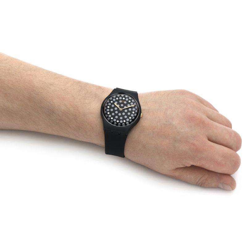 Swatch wristwatch on arm: black rubber strap with speckled black dial.