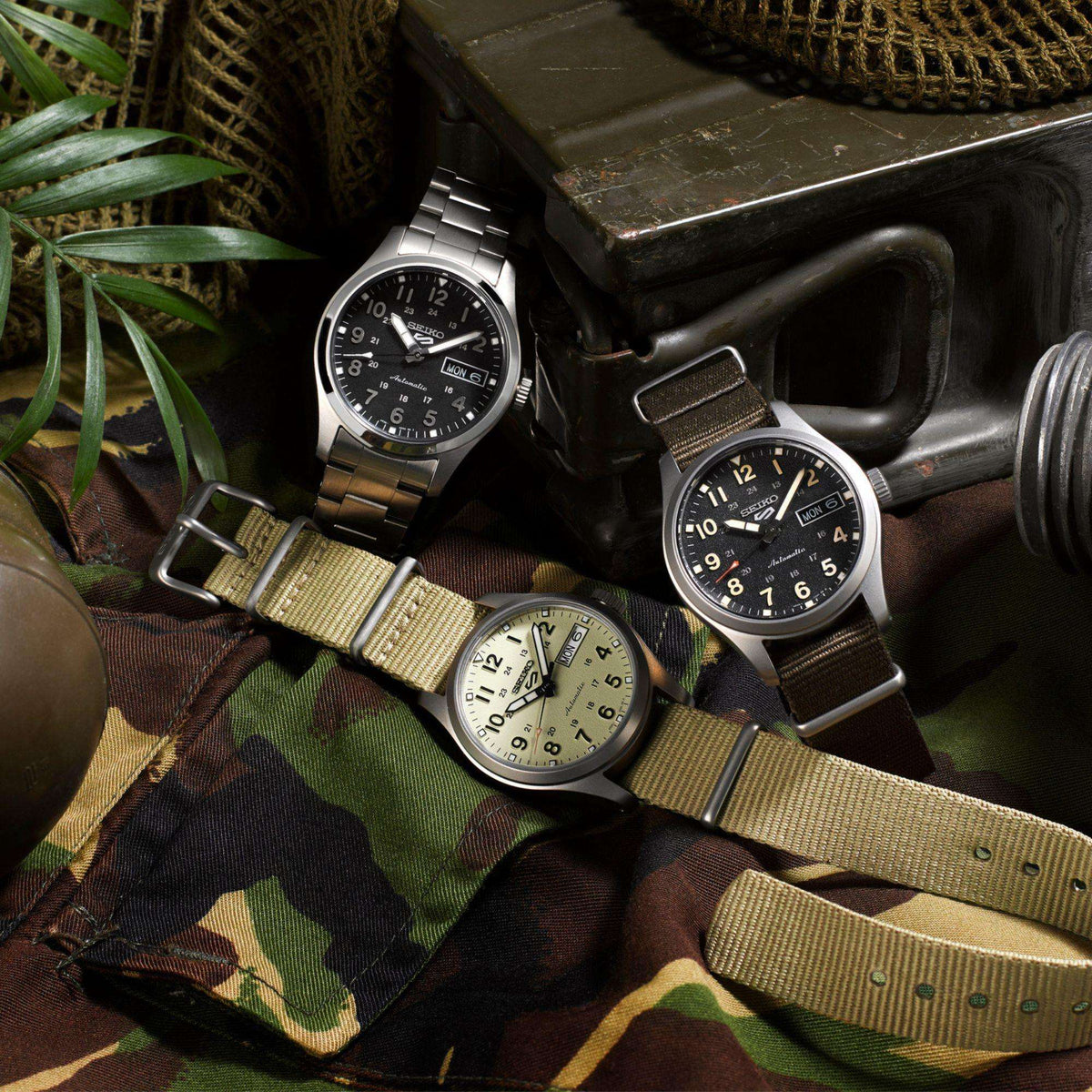 Men's automatic wristwatch with beige dial and beige nylon strap, surrounded by other watches