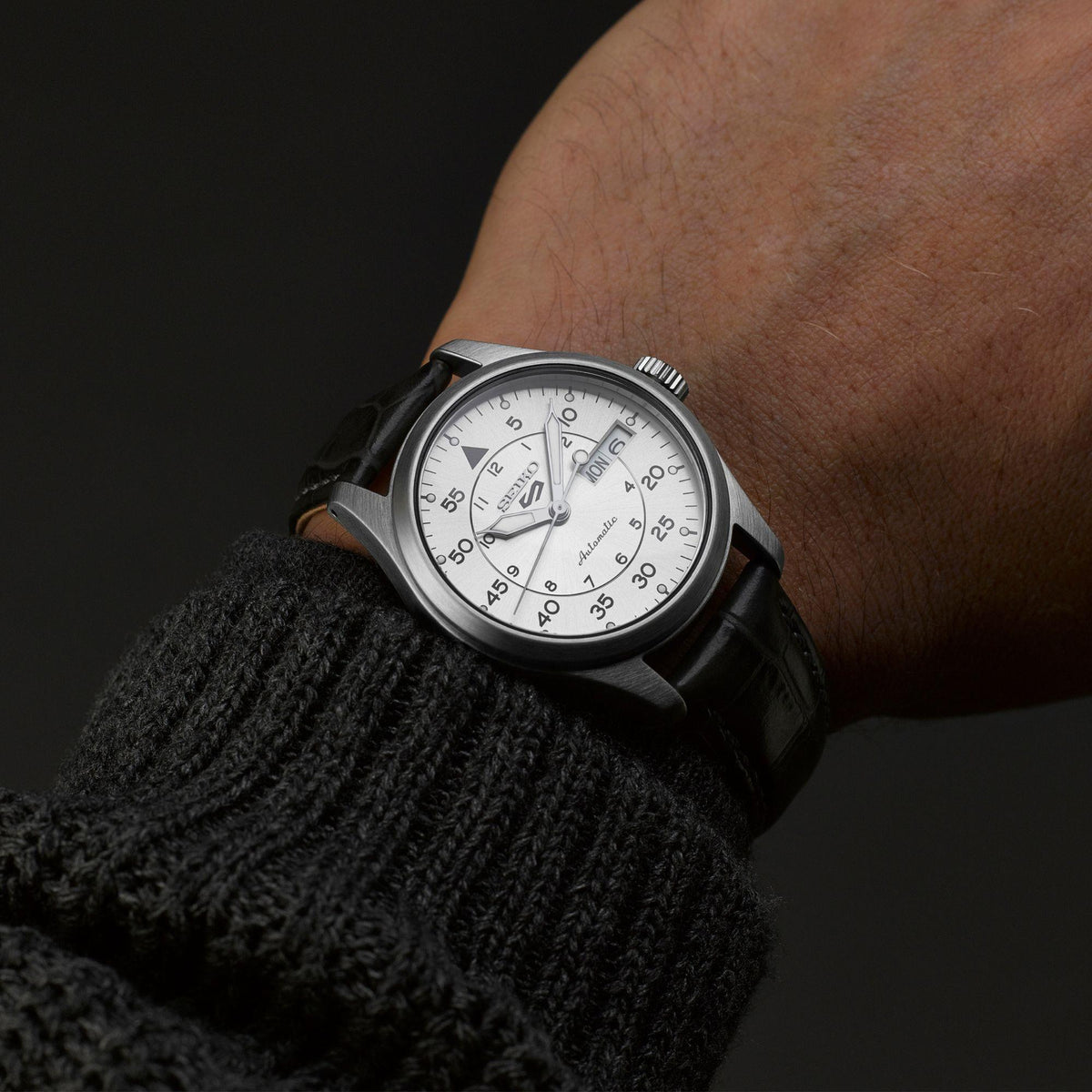 Seiko 5 Sports pilot watch on wrist with champagne dial and black leather strap, date window