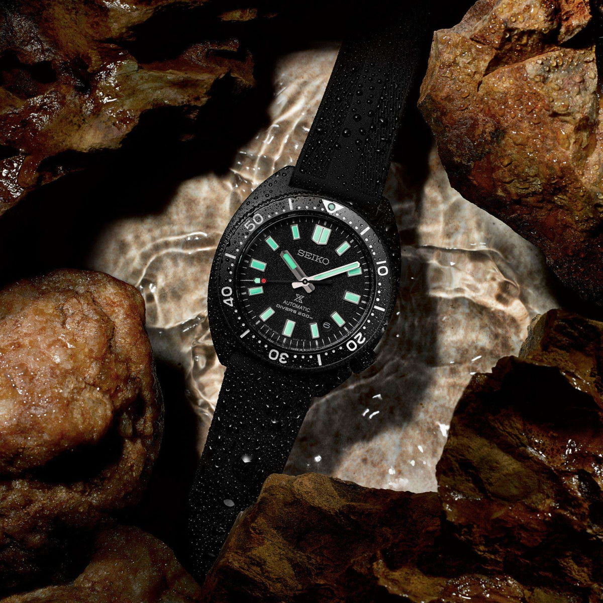 Seiko Prospex Black Series Night Turtle Automatic Black PVD Mens Watch SPB335J1 resting in a shallow pool of water between wet rocks.