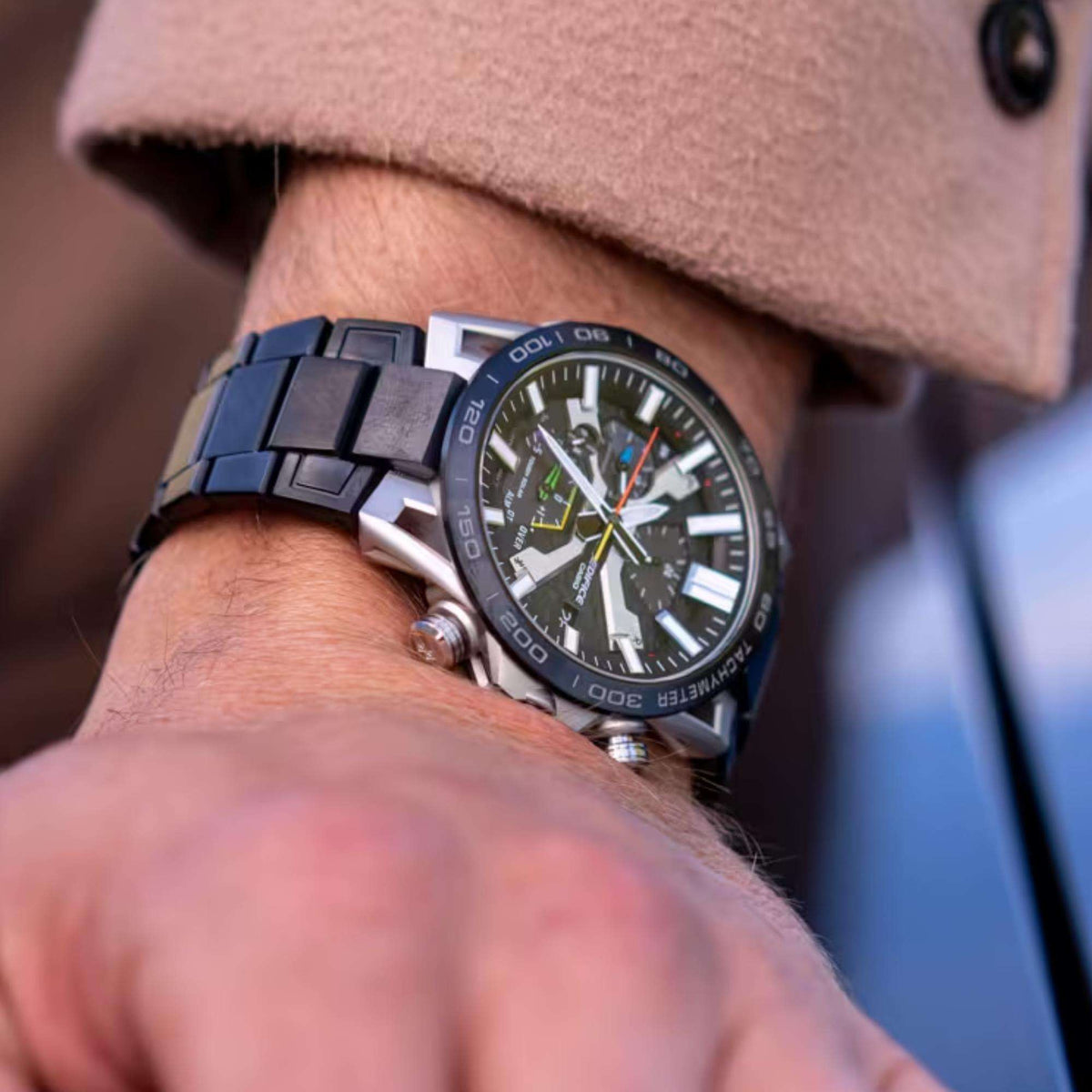 Men's chronograph watch on wrist with dark grey patterned dial and black metal bracelet
