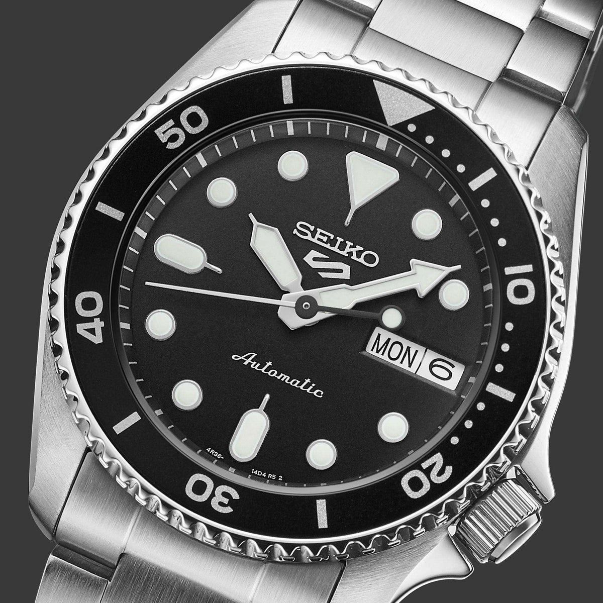 Seiko watch with black dial and silver metal strap on a dark background