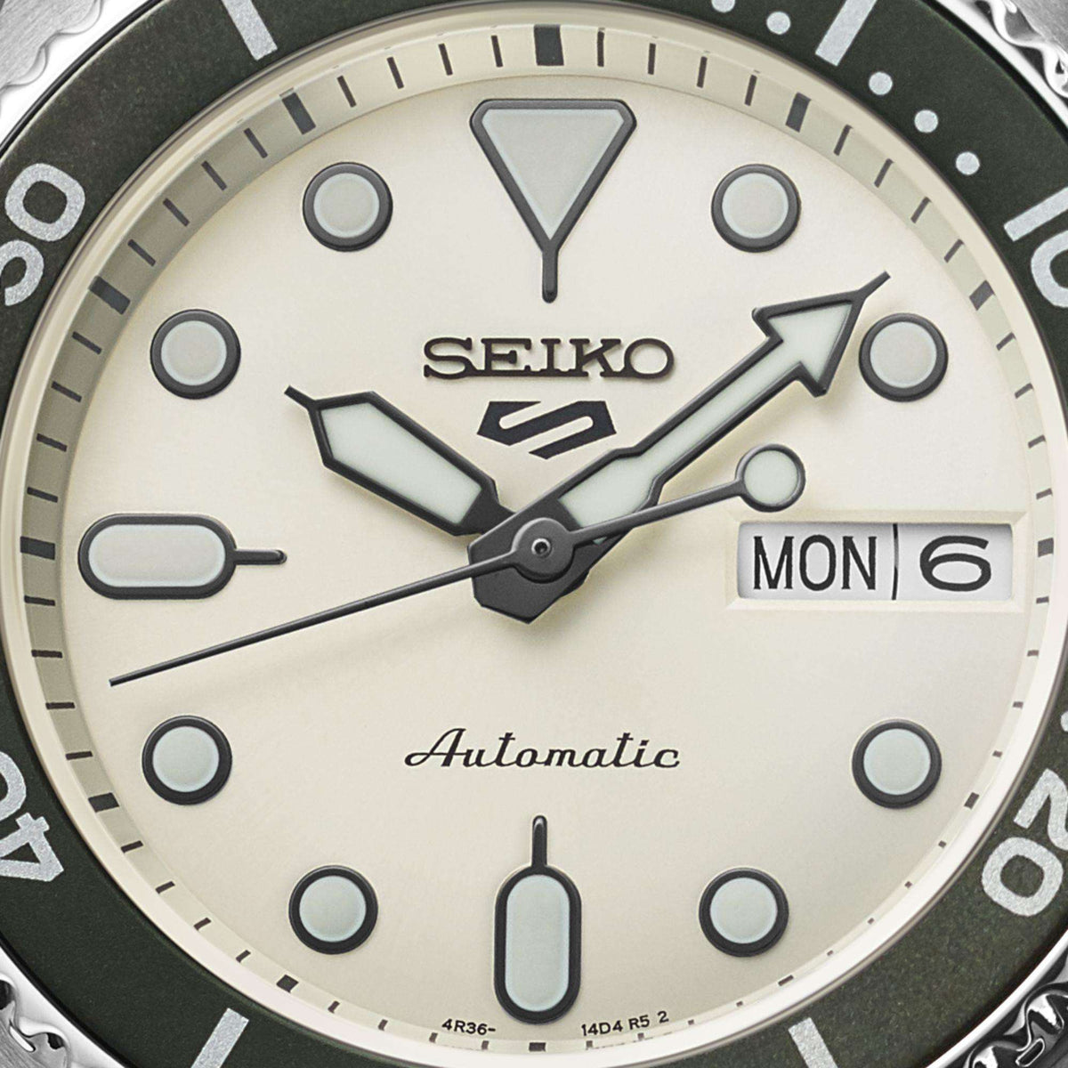 Seiko automatic cream dial close-up with markers, day/date MON 6, and arrow hands