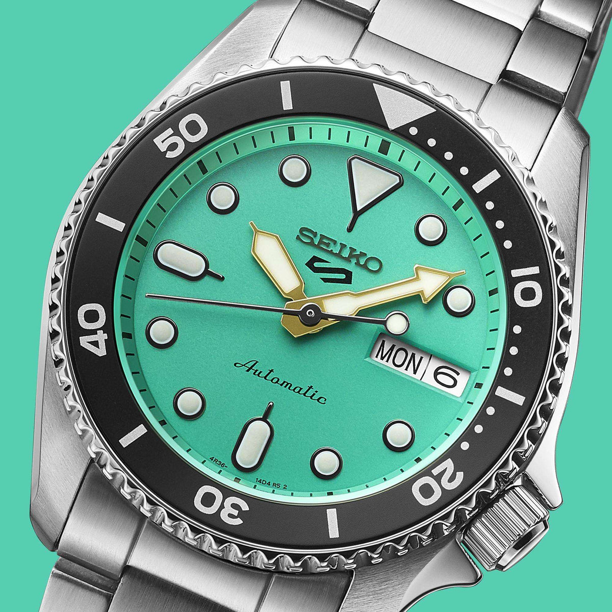 Seiko 5 Sports SKX Teal Dial watch face, focusing on the luminescent indices and hands against a matching teal backdrop.
