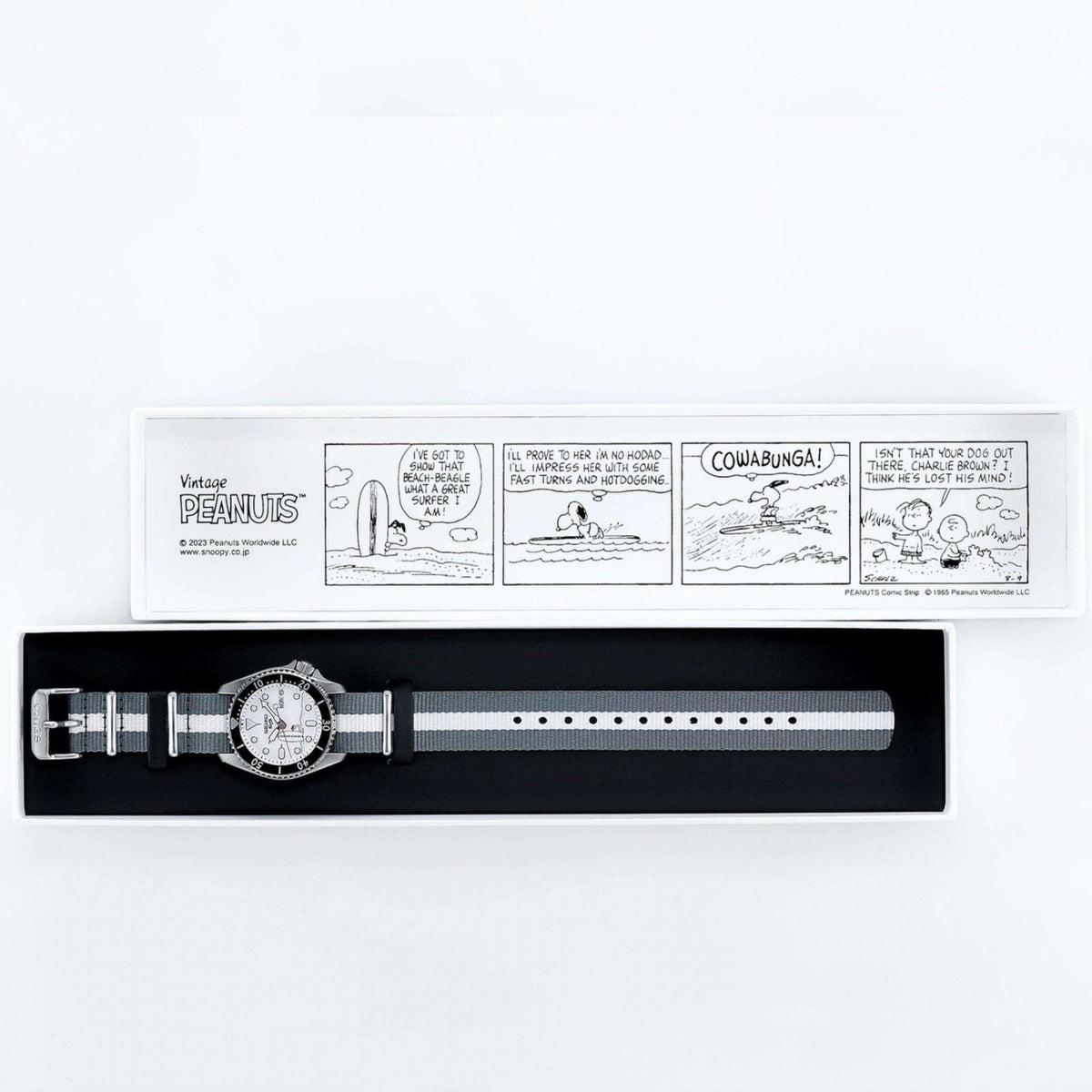 Seiko 5 Sports X Peanuts Surfboard Automatic White Dial Watch SRPK25K1 inside its presentation box with a Peanuts comic strip printed on the inside.
