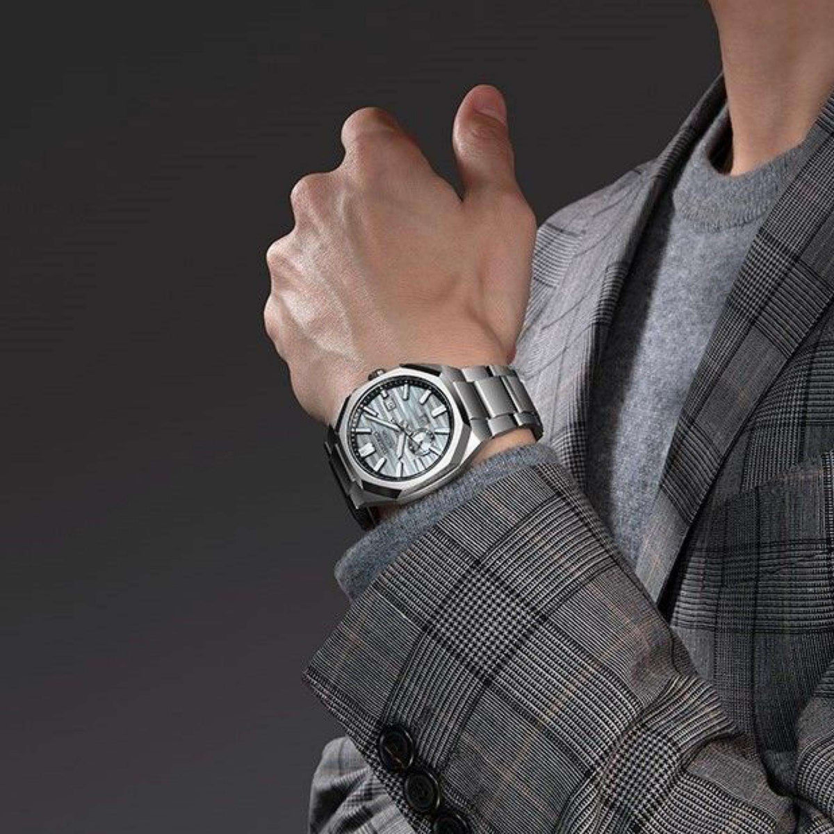 Seiko Astron titanium watch on wrist paired with a grey plaid suit jacket, highlighting its style as a luxury dress and sports watch.