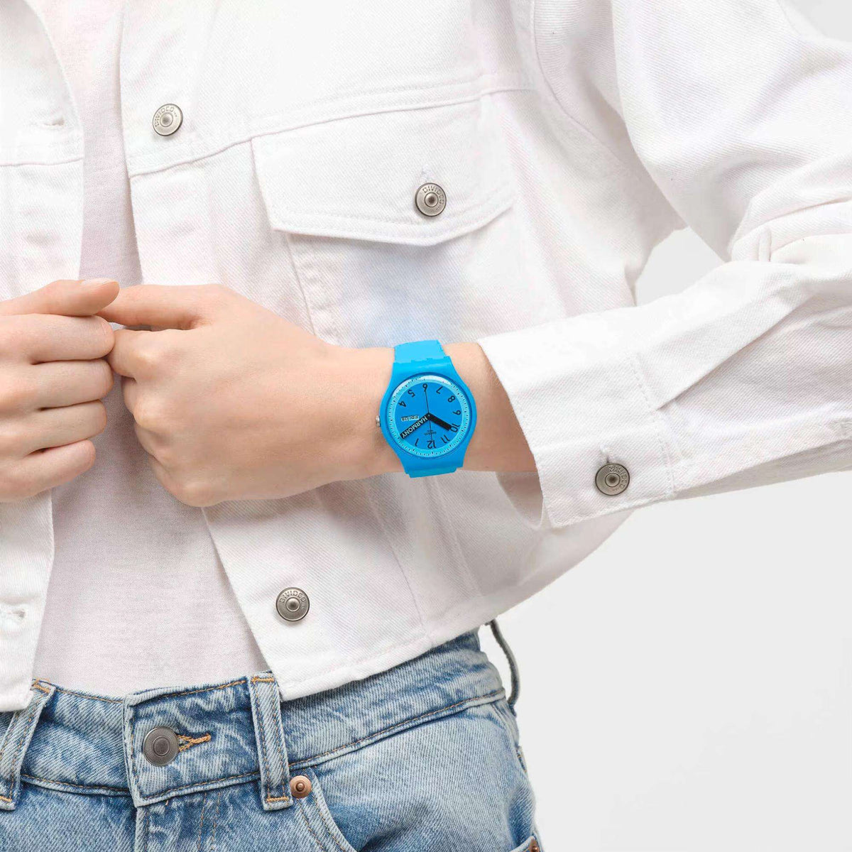 Blue quartz wristwatch on wrist with blue dial and black hands over a white shirt sleeve.
