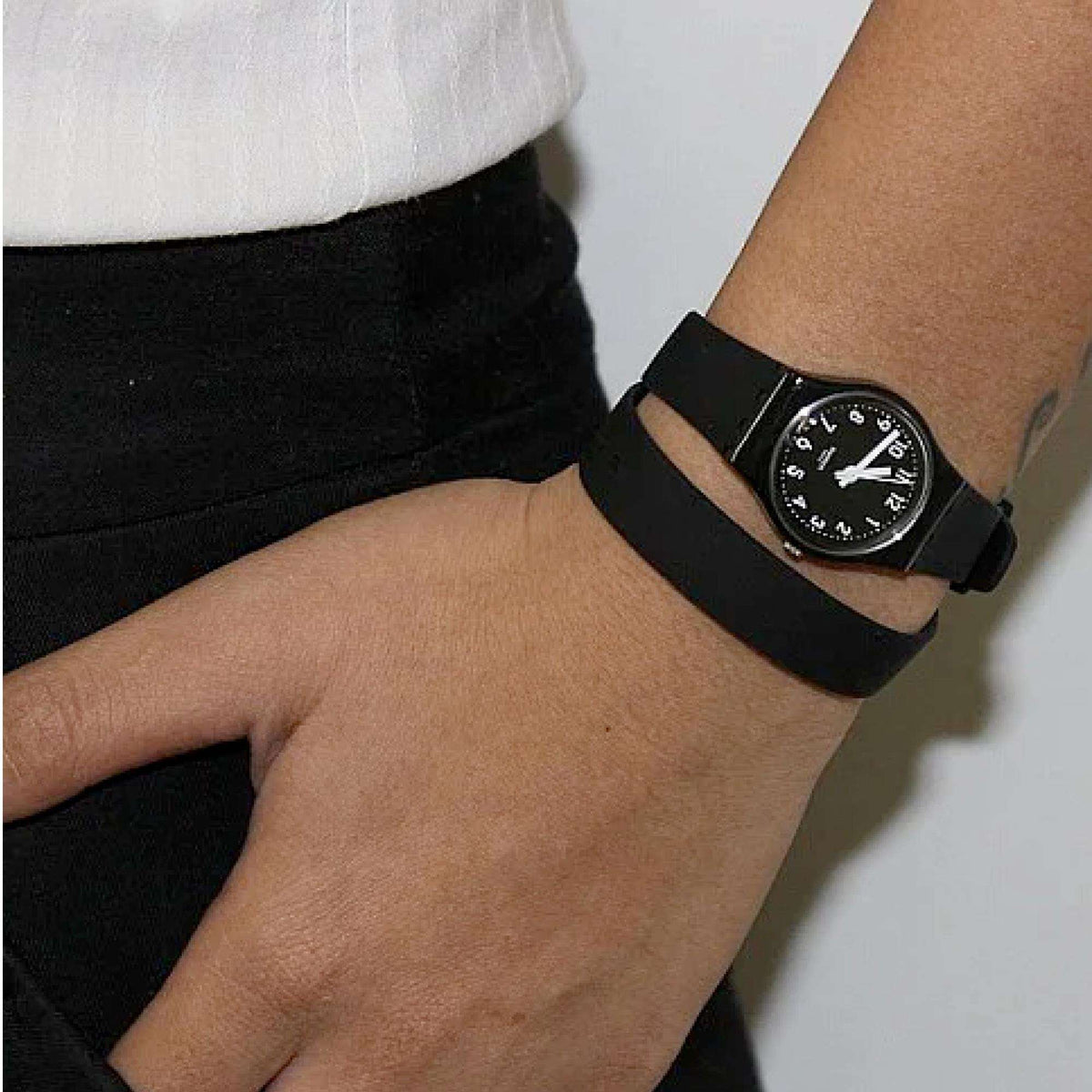 Black wristwatch on a person’s arm, round dial with white markers on silicone band
