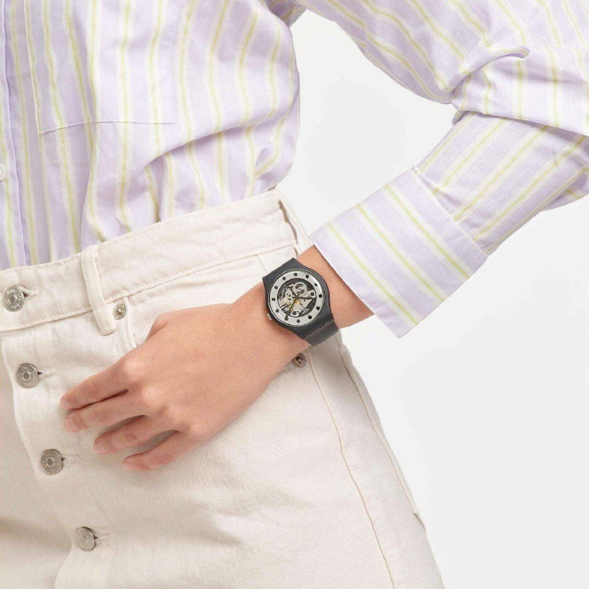 Quartz watch on wrist with black rubber strap and silver skeleton dial, on light shirt