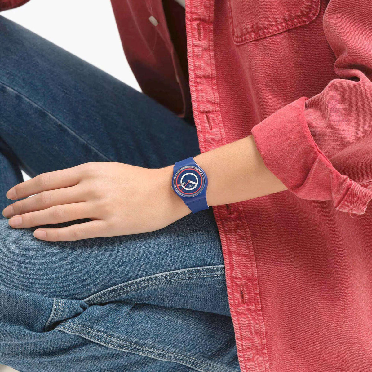 Blue silicone watch on wrist with round red/white ring dial and Fri 28 date display