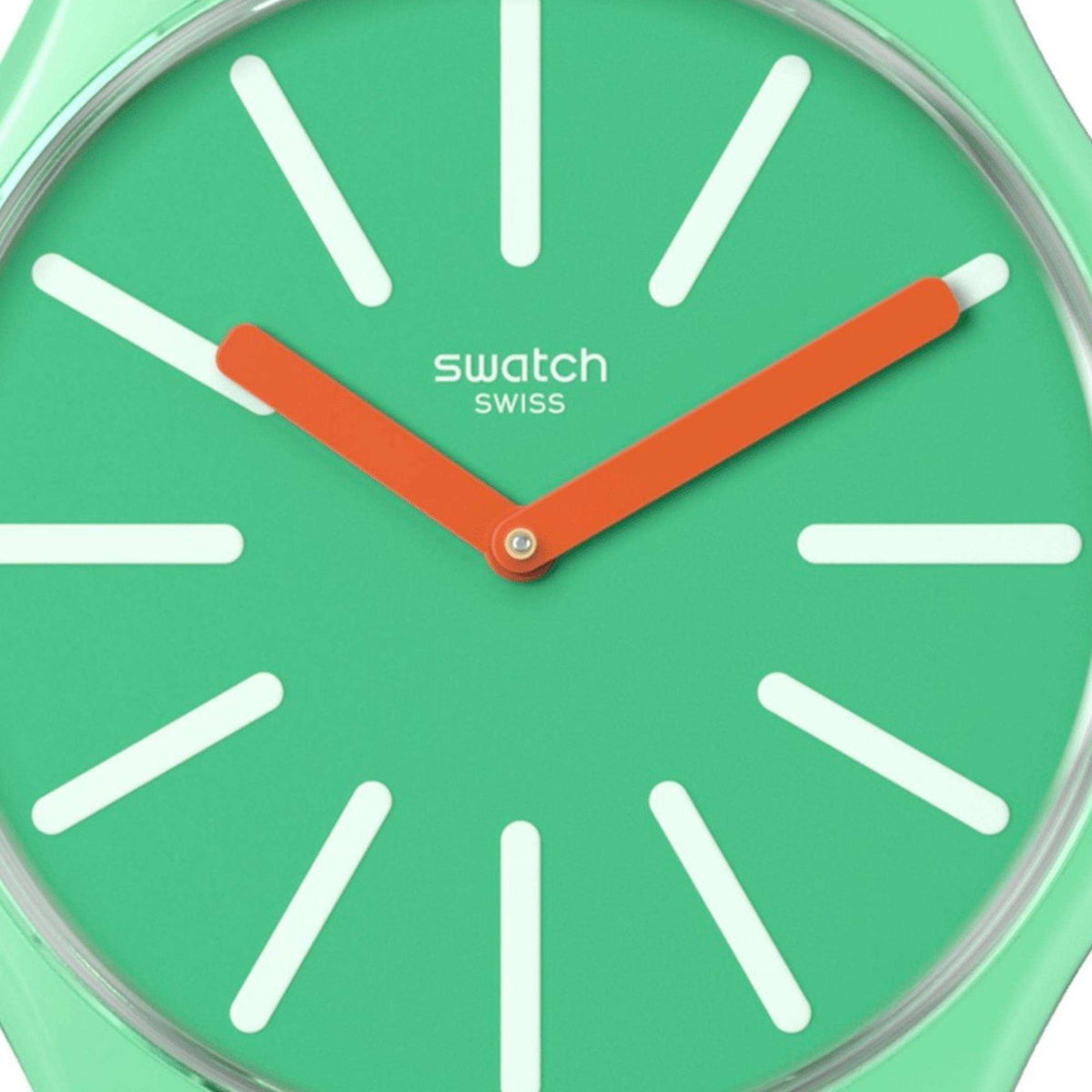 Green watch dial close-up with white hour markers, orange hands, Swatch logo