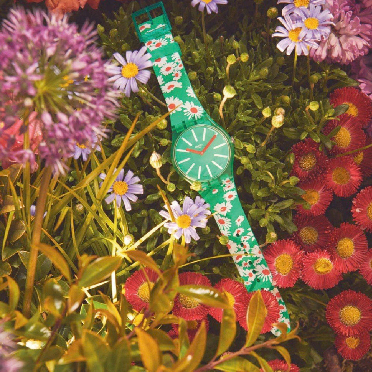 Green floral watch on wrist, round green dial with white markers and orange hands