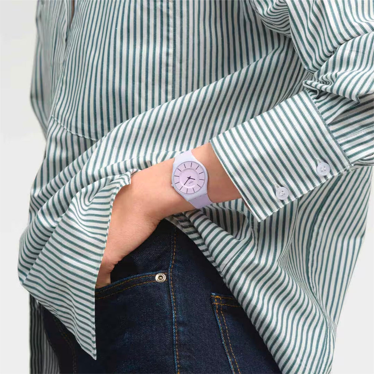 Violet watch on wrist with lilac strap, worn under striped blue-and-white shirt