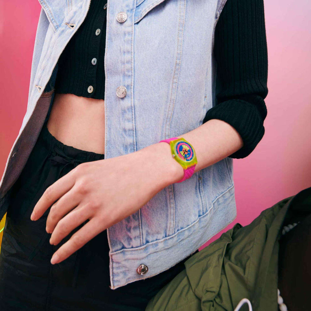 Swatch neon ladies watch on wrist: pink textured strap, rainbow dial with yellow trim