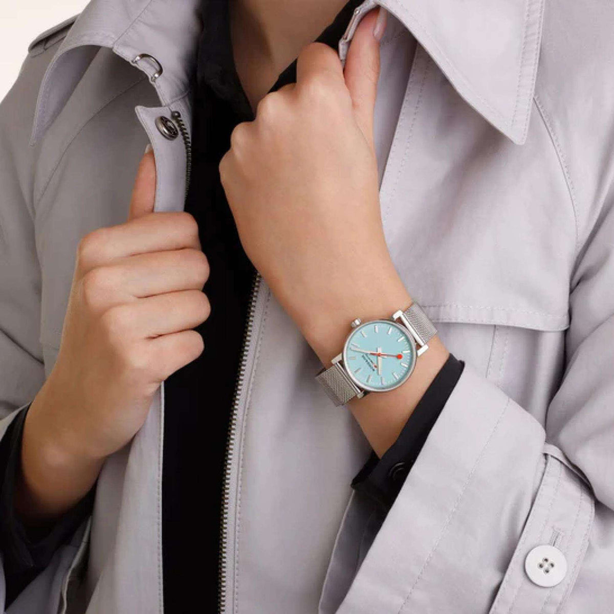 Mondaine Evo2 watch on sleeve wrist, turquoise dial, red hands, steel mesh strap