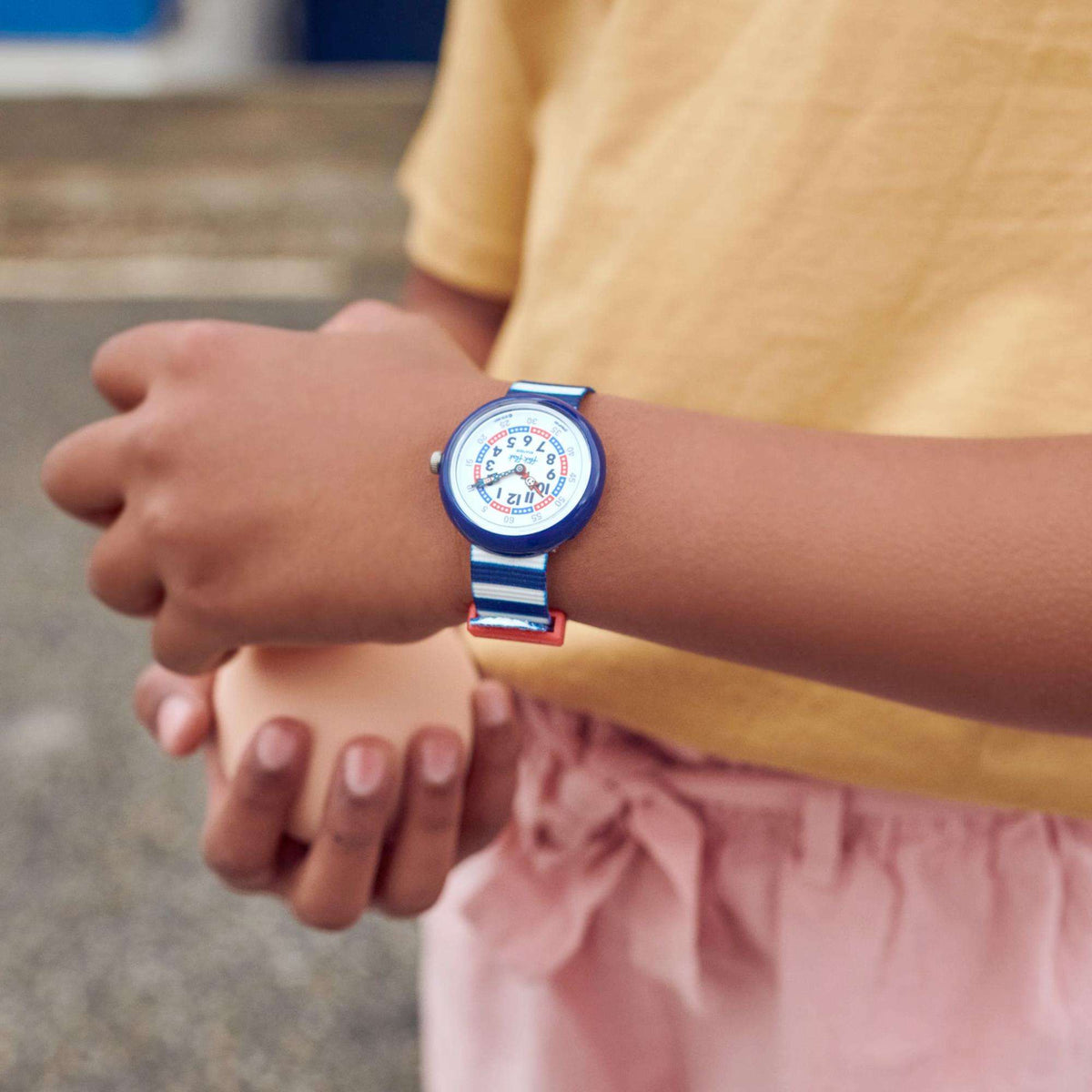 Children's wrist watch on arm, blue bezel with white dial and red-blue details
