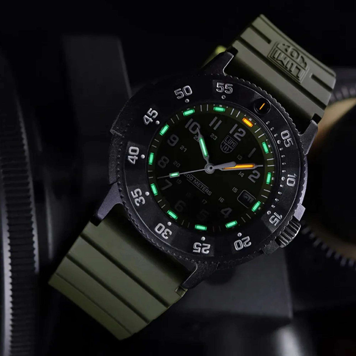 Black diver quartz watch with green glowing dial and orange second hand on rubber strap