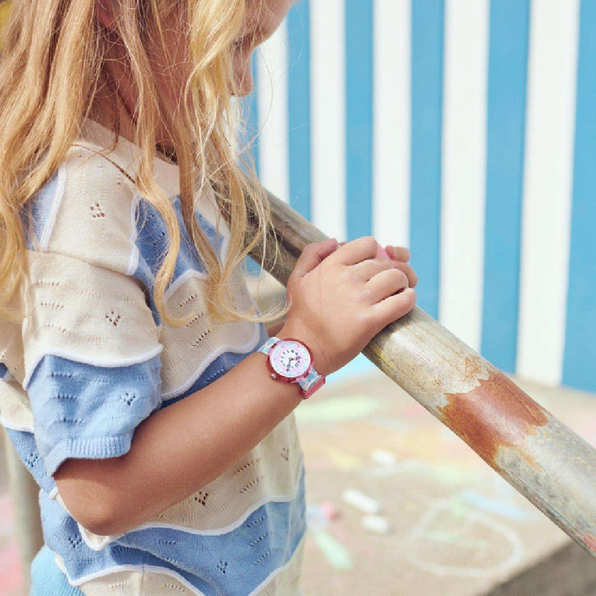 Kids watch on child’s wrist, white and blue patterned fabric strap with pink bezel
