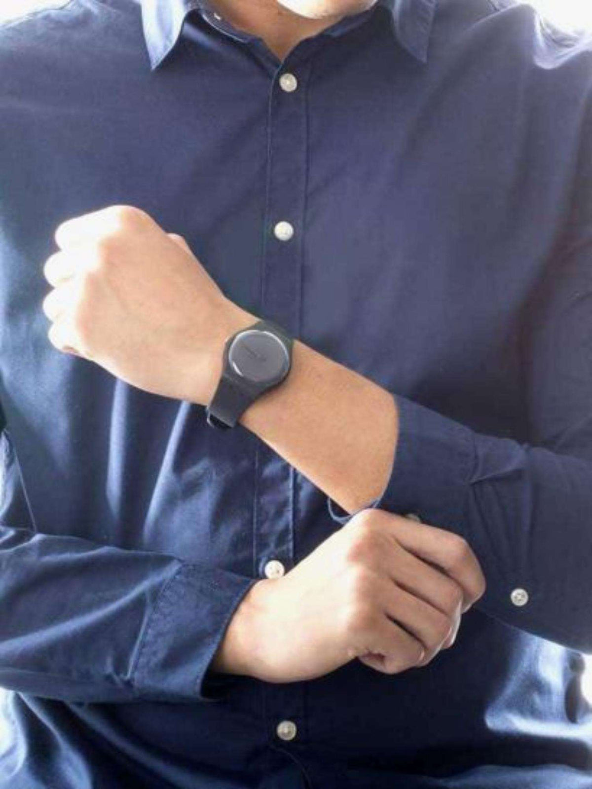 Swatch black dial watch with black silicone strap on male wrist