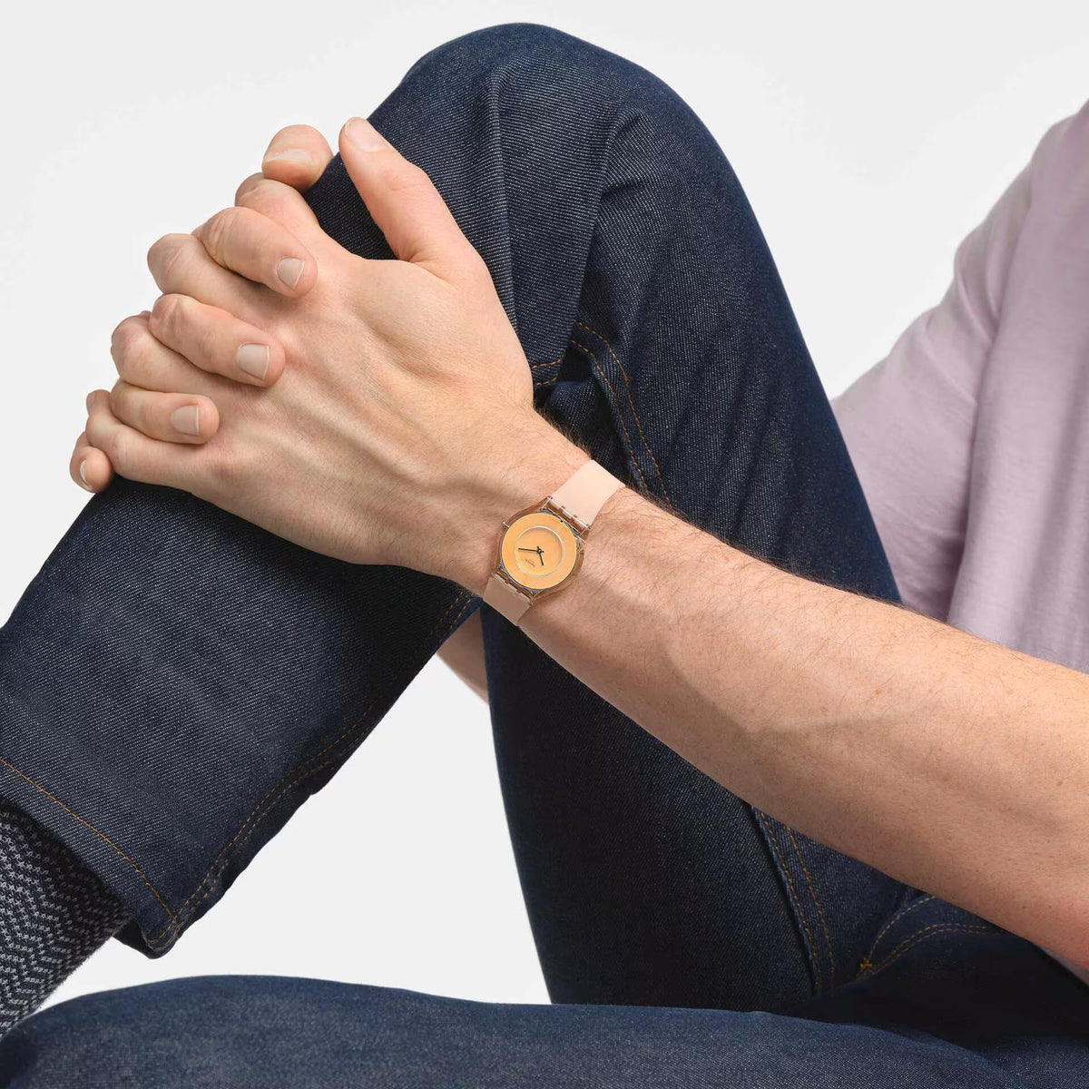 Peachy pink silicone strap watch worn on wrist with orange dial and gold-tone case