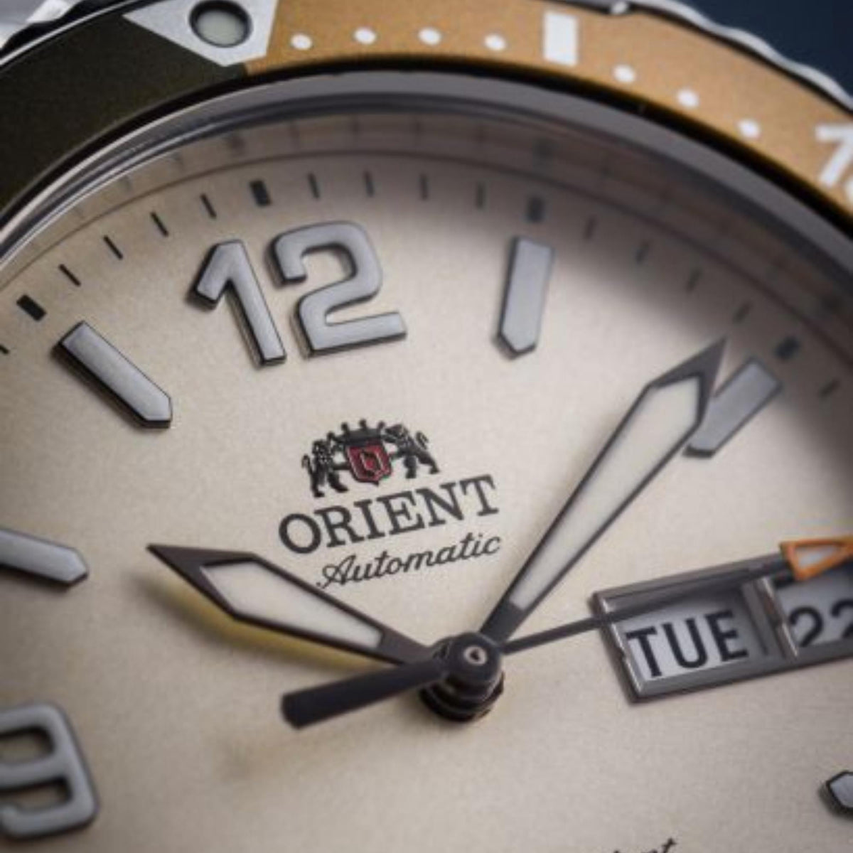 Close-up of ivory watch dial with Orient logo, Automatic text, and day-date window