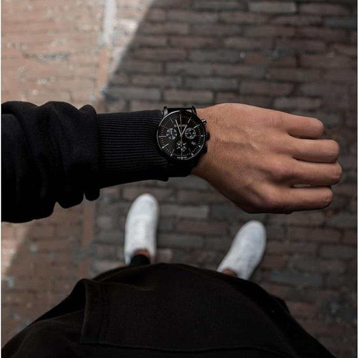 Men's Wenger chronograph watch on wrist with black dial and black mesh bracelet