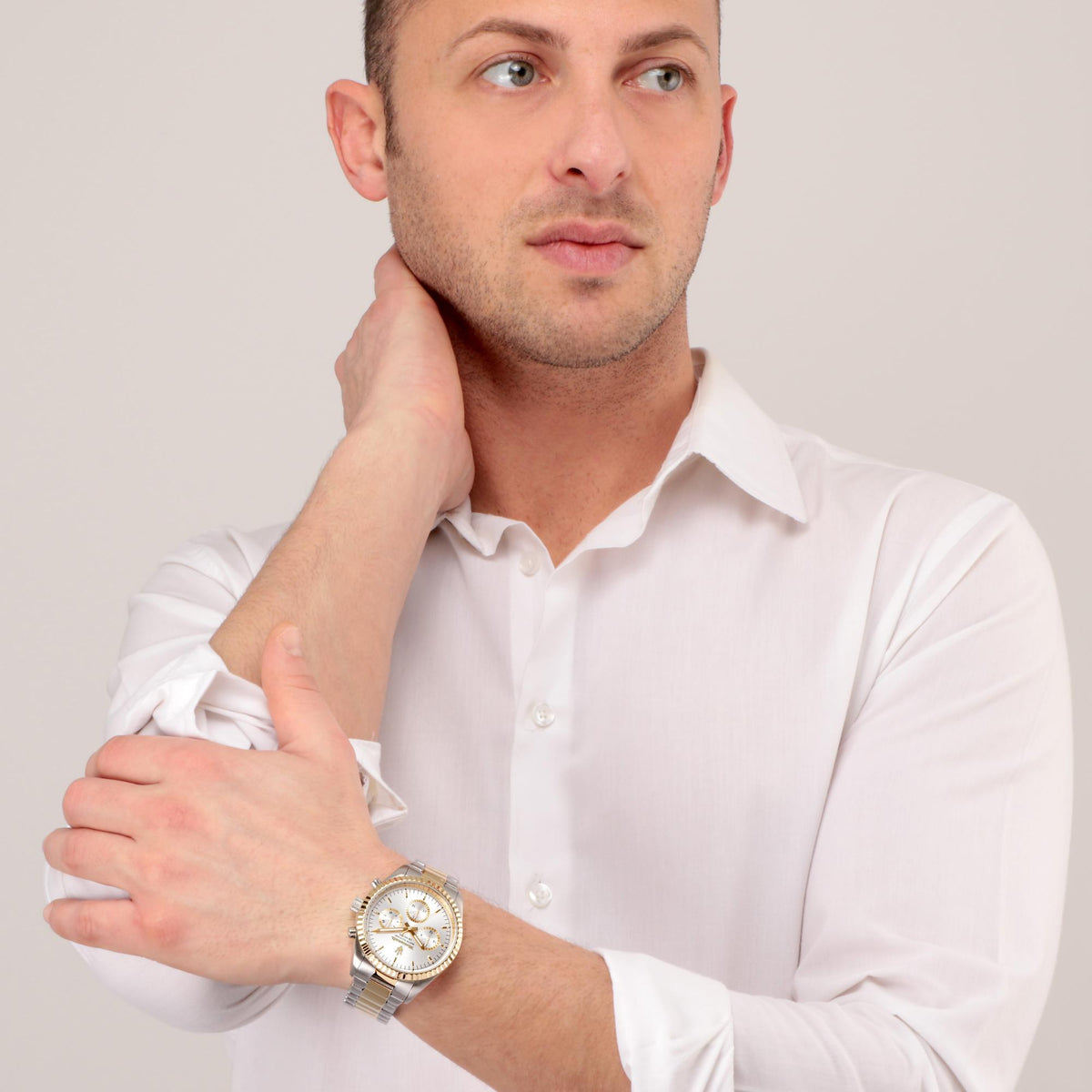 Two-tone steel chronograph watch on men’s wrist with silver dial and gold bezel