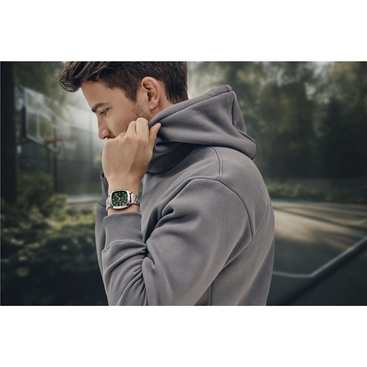 Men's stainless steel watch with green dial and bracelet, worn on wrist