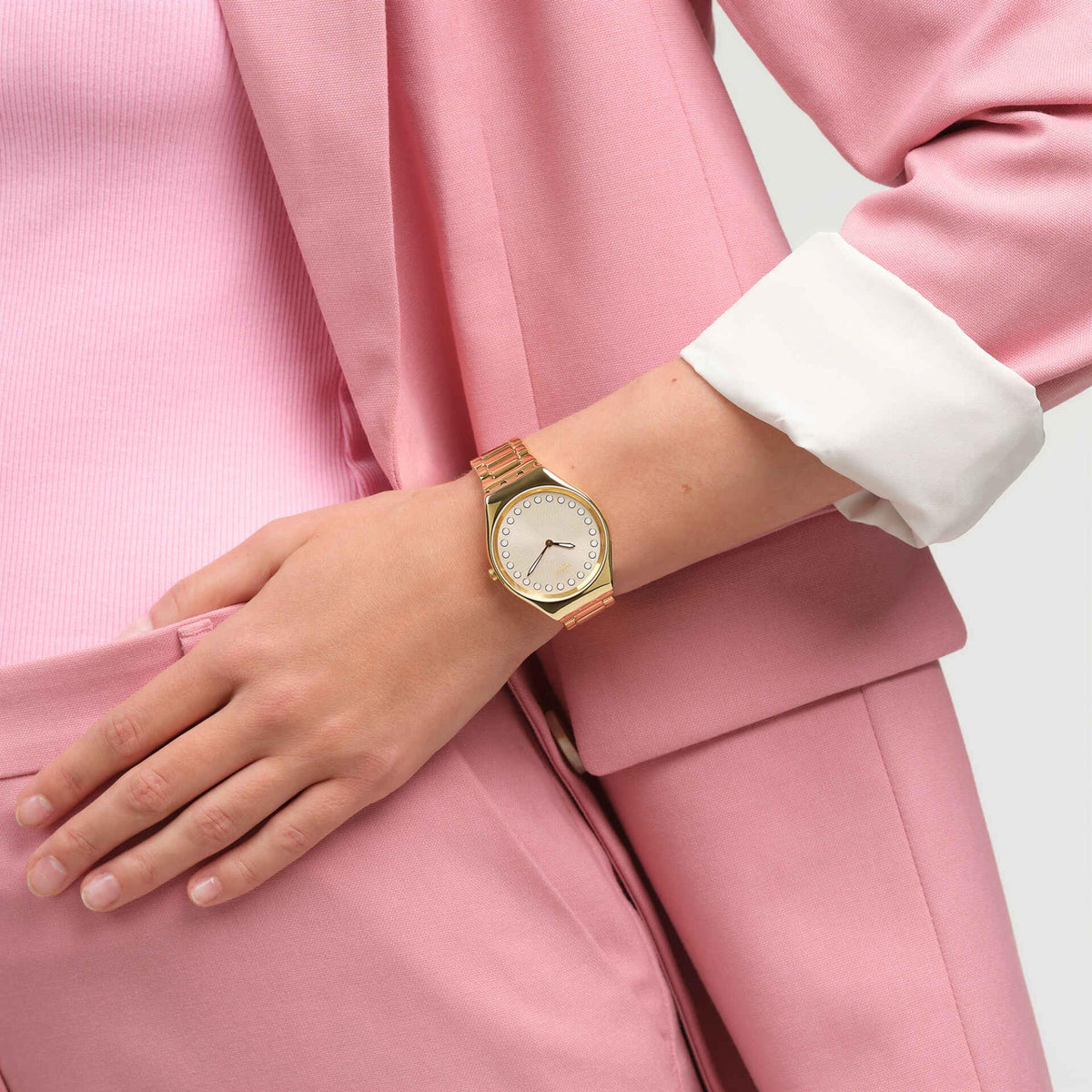 Unisex gold-tone quartz watch on wrist with beige dial, white bezel dots, gold bracelet