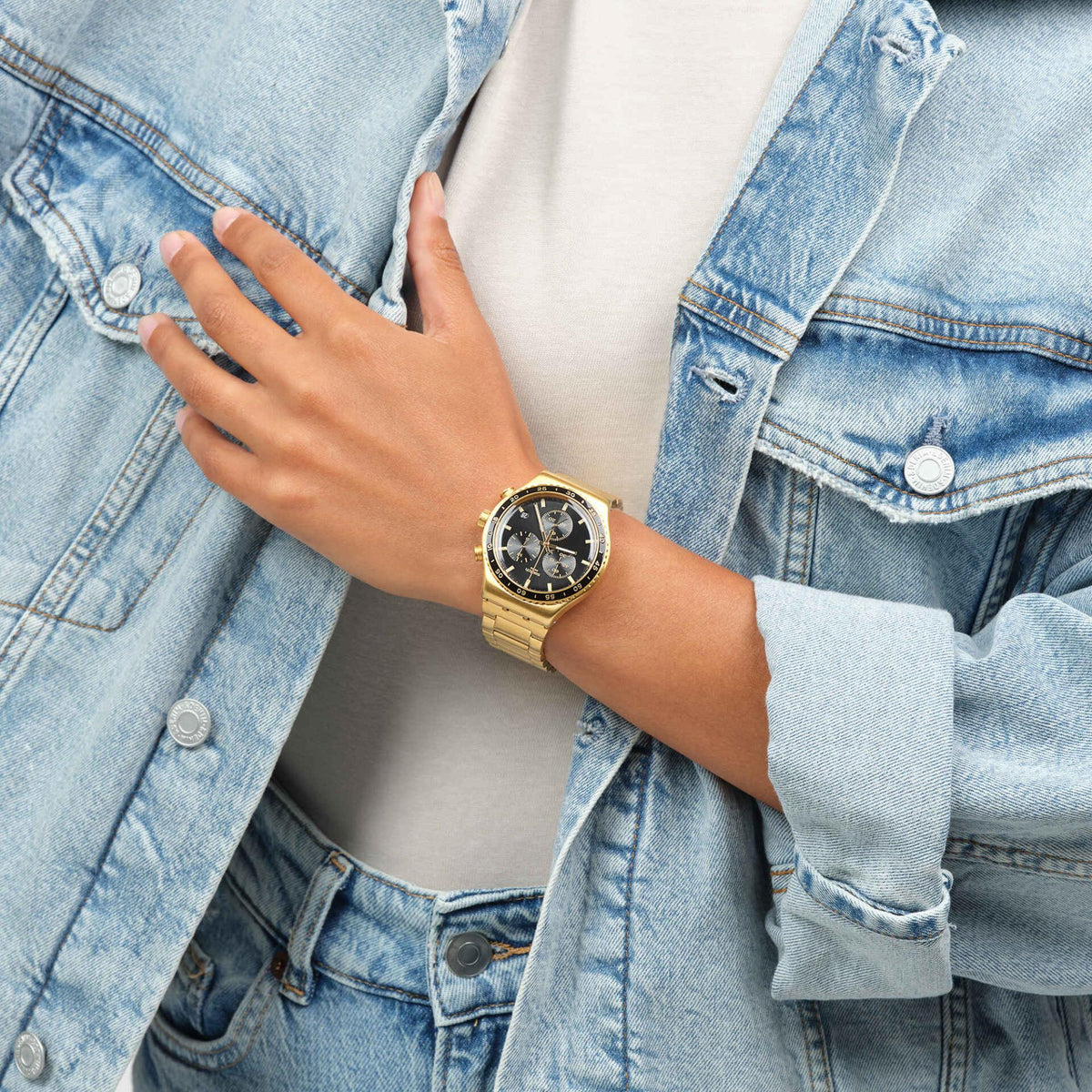 Gold-tone bracelet watch with black dial worn on wrist; three subdials visible