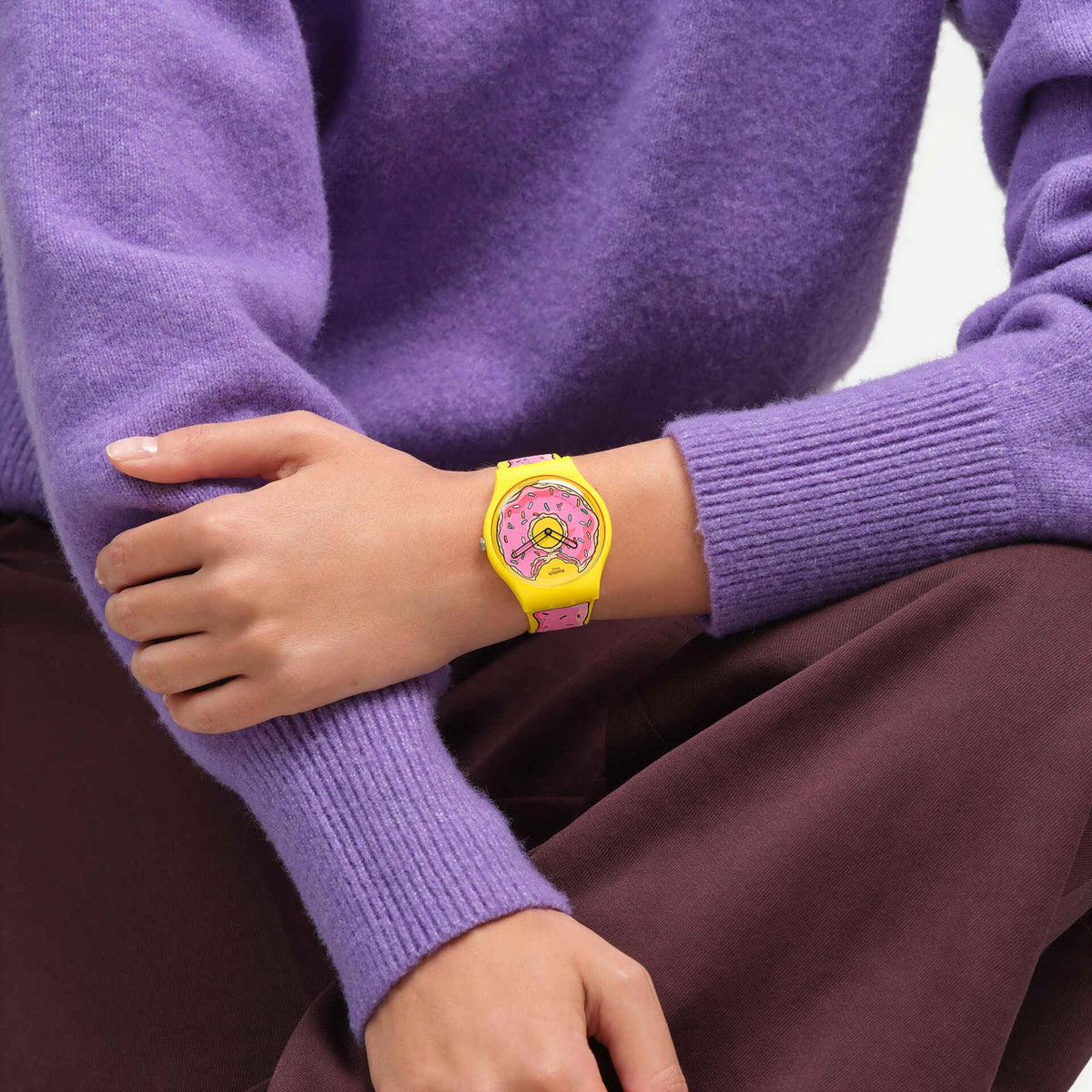 Donut graphic watch on wrist with yellow silicone band over a purple sweater