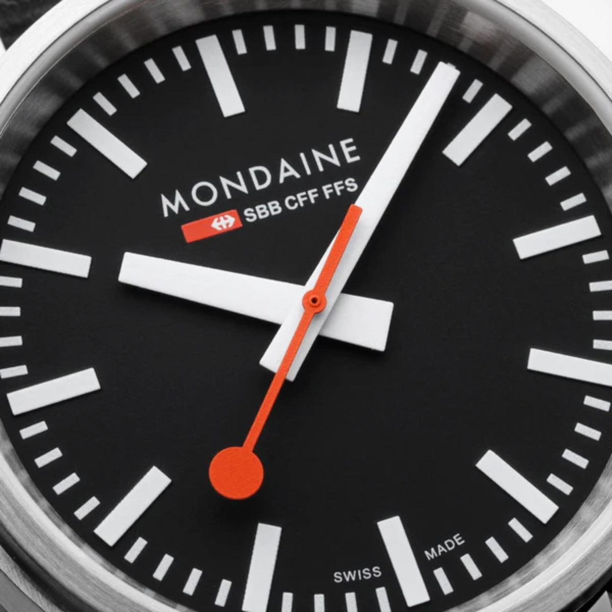 Mondaine stop2go dial close-up with bold markers and orange seconds hand on black face