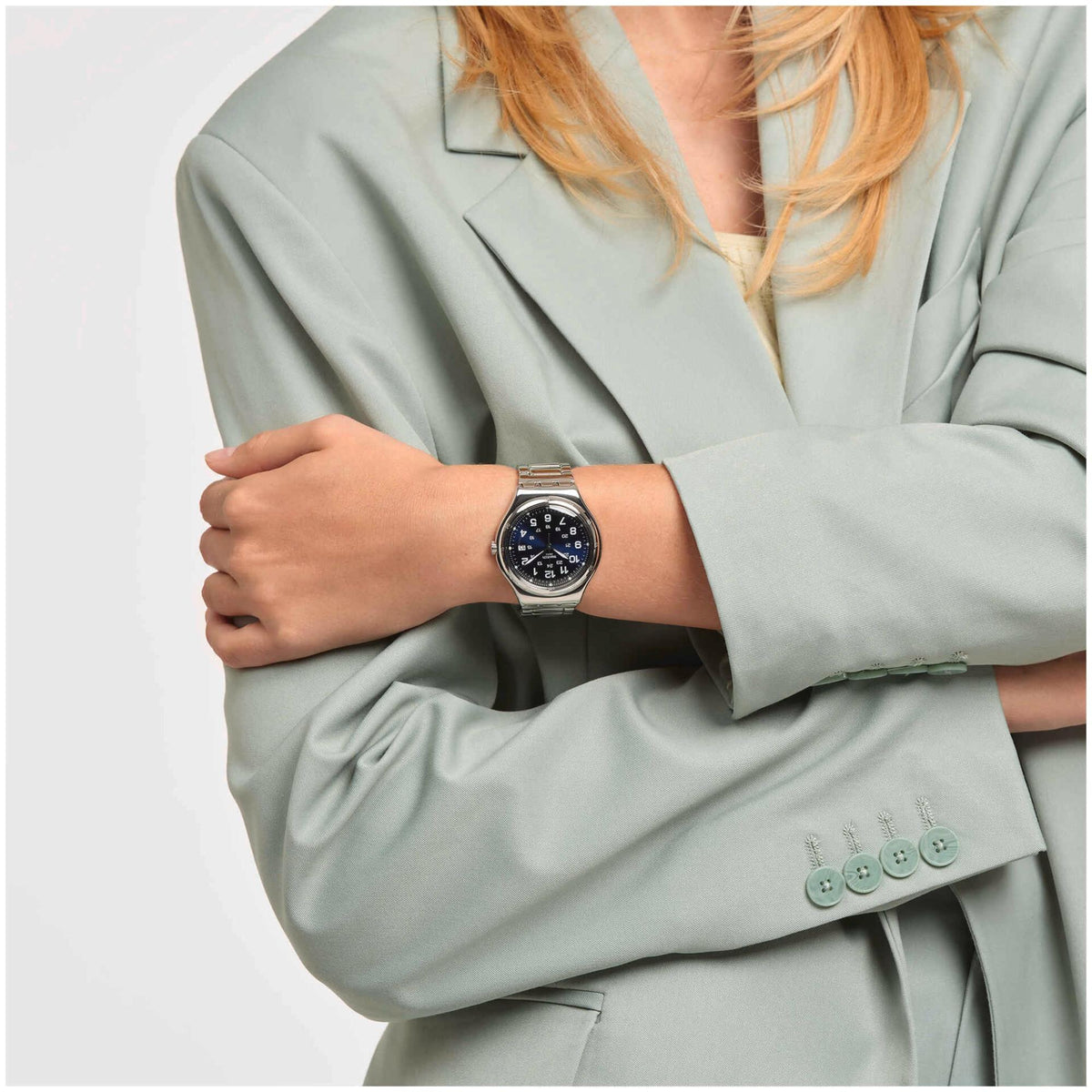 Stainless steel wristwatch worn on wrist with dark blue dial and metal bracelet