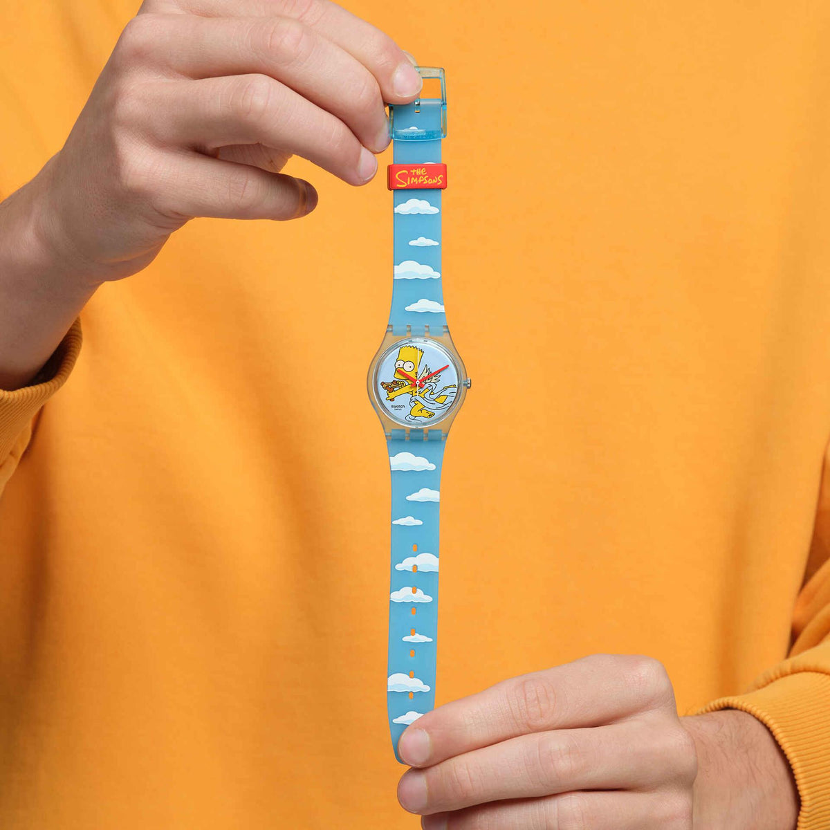 Bart Simpson wristwatch on arm with blue cloud-pattern strap being adjusted