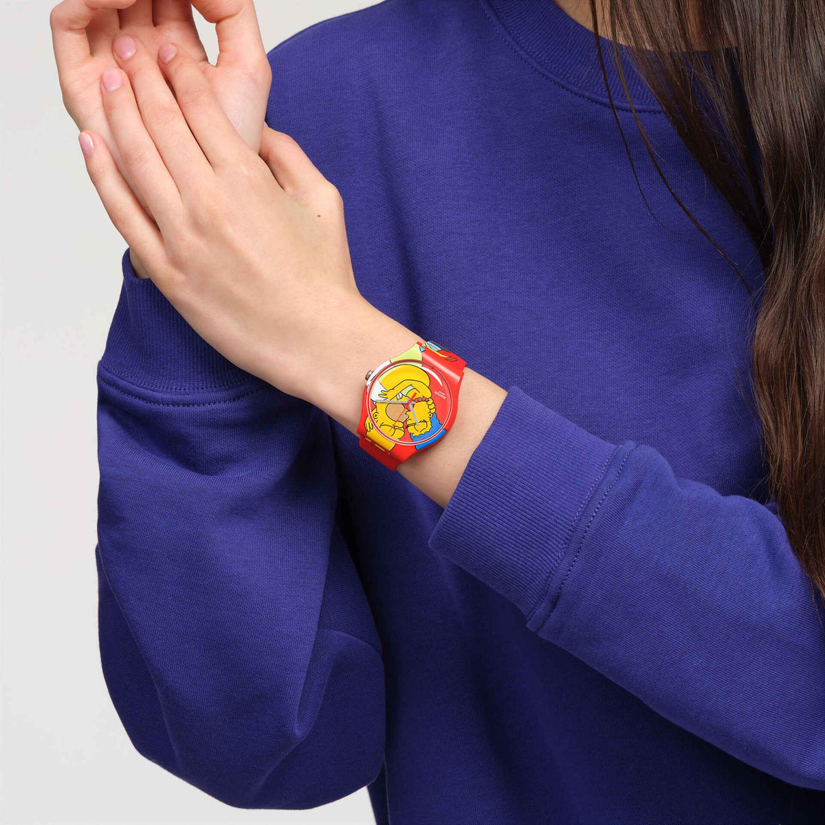 Red silicone Swatch watch with cartoon dial, worn on wrist
