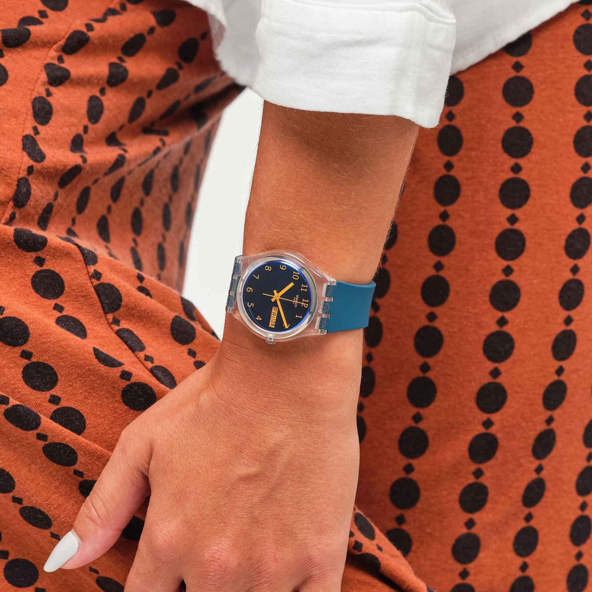 Swatch bio-sourced quartz watch on wrist, teal strap, blue dial, orange hands