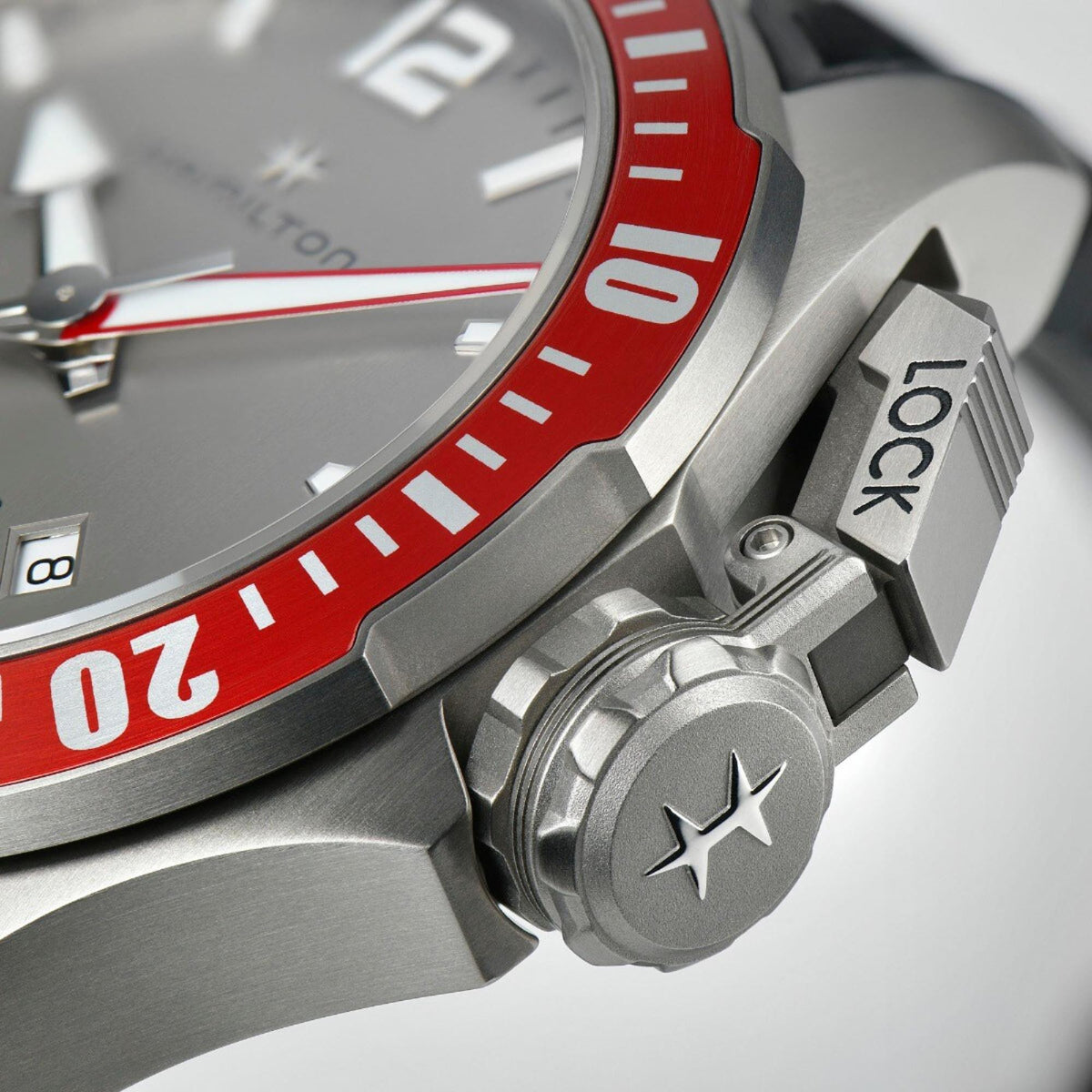 Diver watch crown detail with star emblem on steel case and black rubber strap