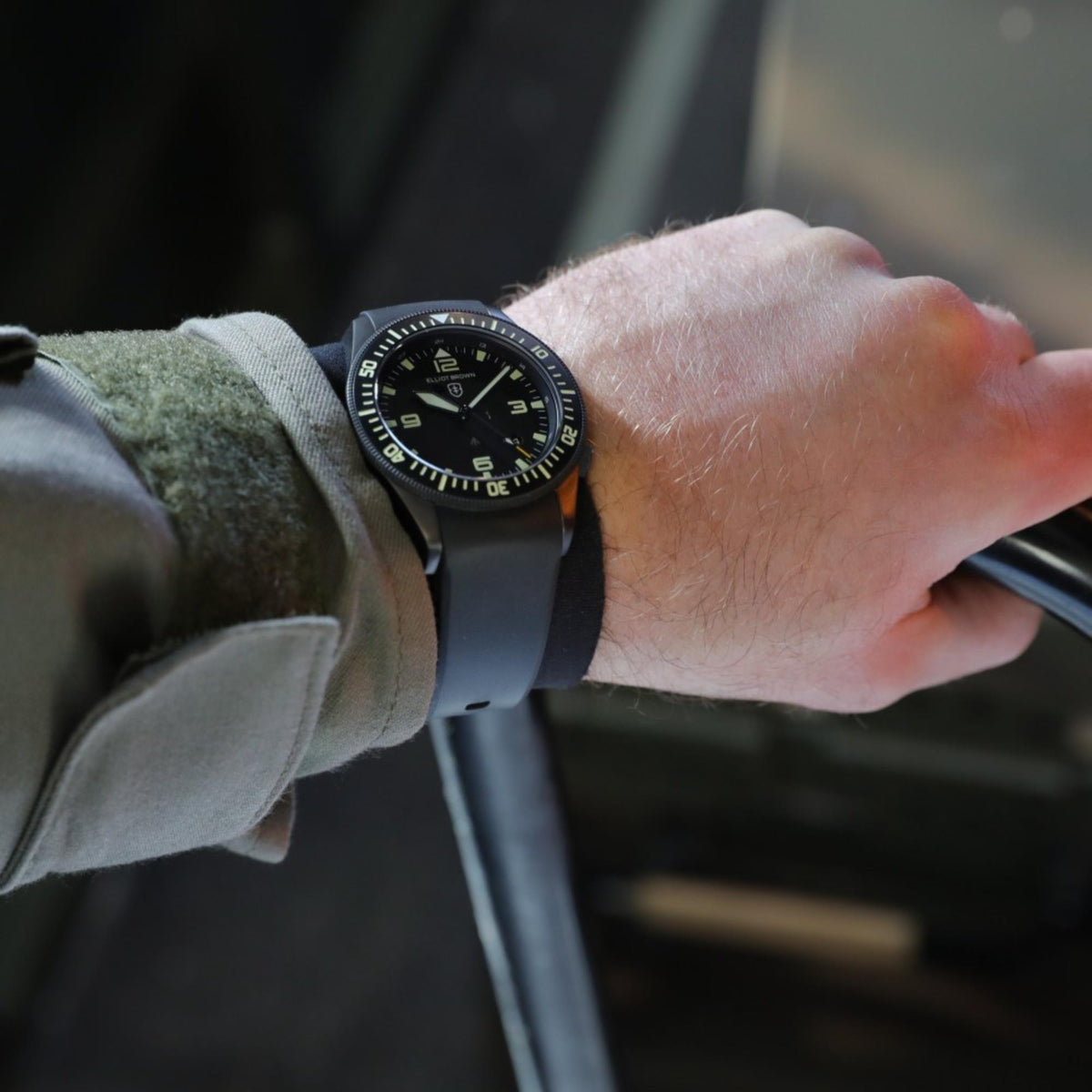 Men’s black rubber strap watch worn on wrist, black dial with green markers