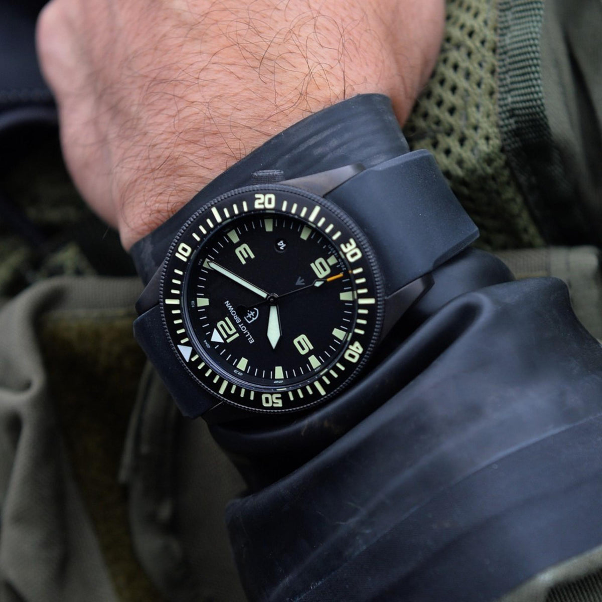 Men’s black rubber strap watch on wrist, black dial with green accents and bezel numerals