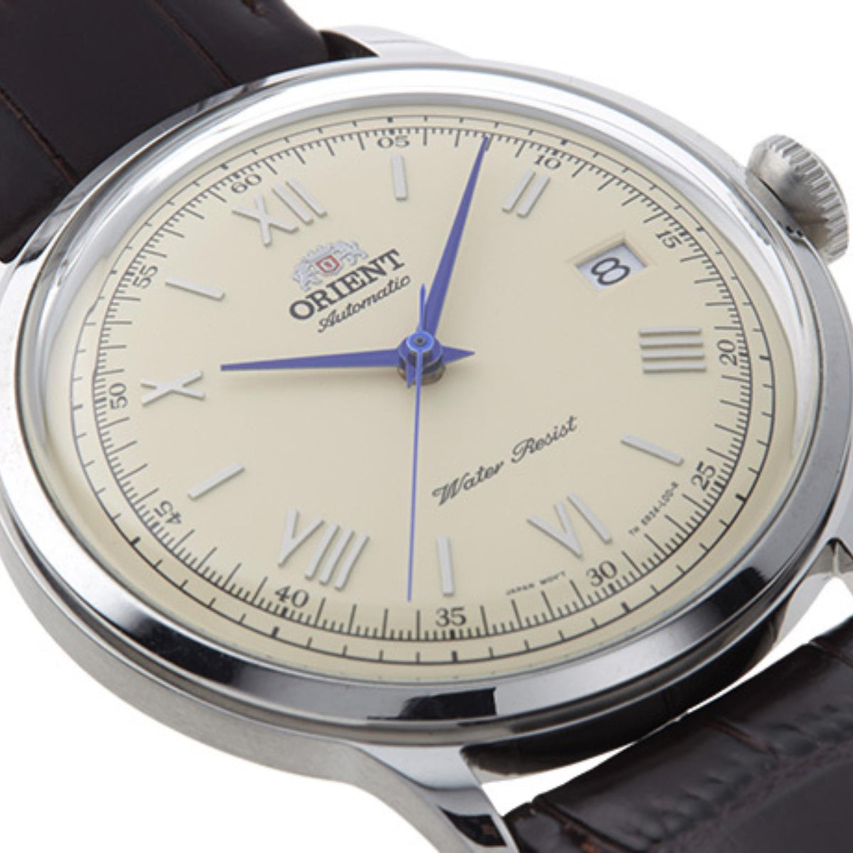 Close-up men's watch face with cream dial, blue hour markers, blue hands, leather strap