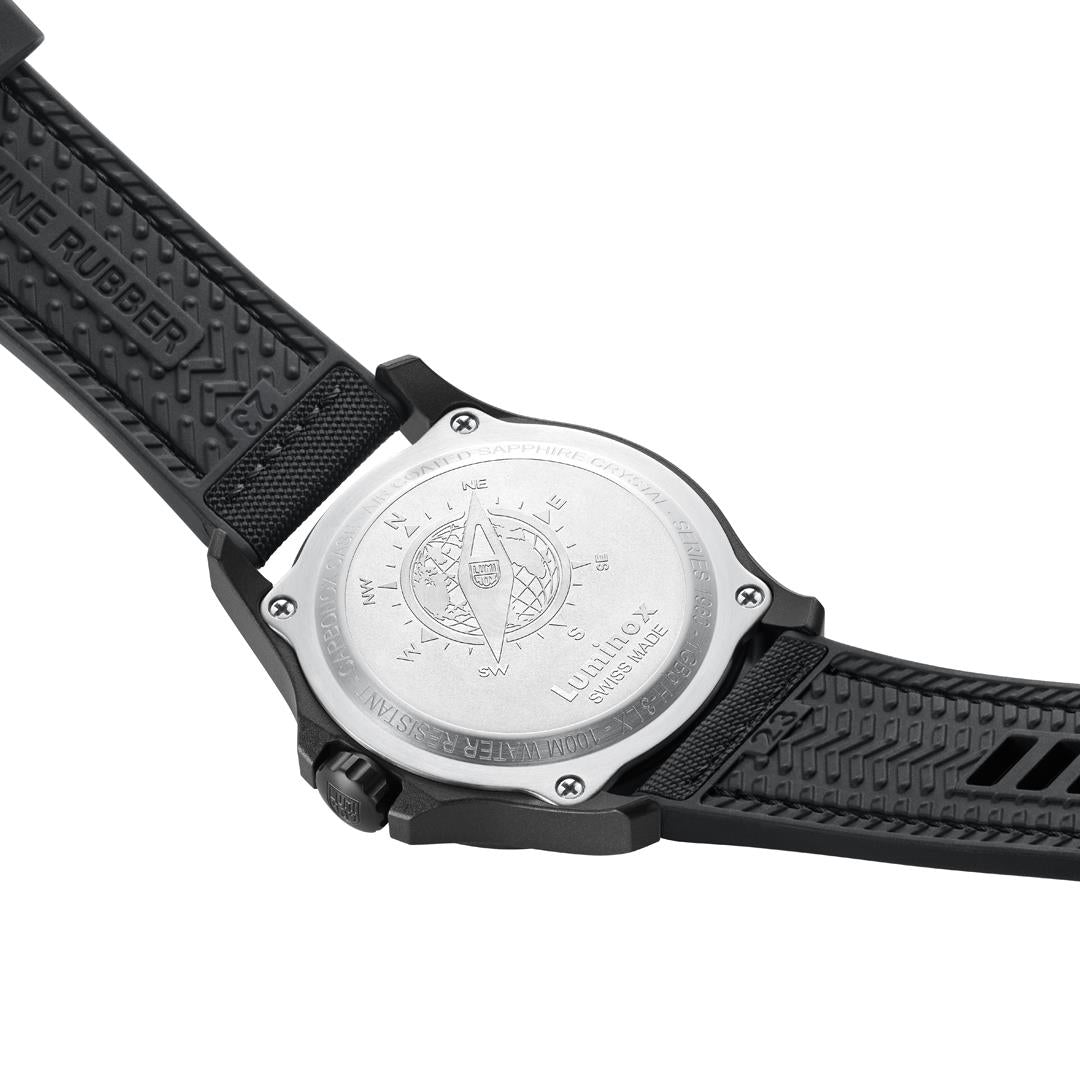 Round caseback on men's black rubber watch strap with engraved map and crest