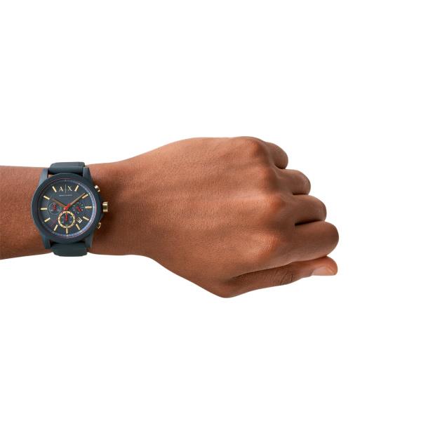 Men's chronograph watch on wrist with black silicone strap and dark dial.