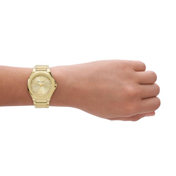 Gold-tone steel quartz watch worn on wrist with champagne dial and link bracelet