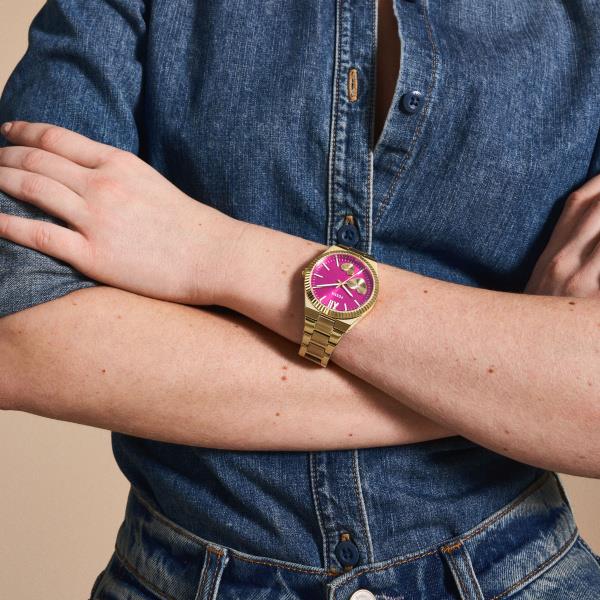 Fossil ladies quartz watch on wrist with gold-tone bracelet and pink dial with heart details