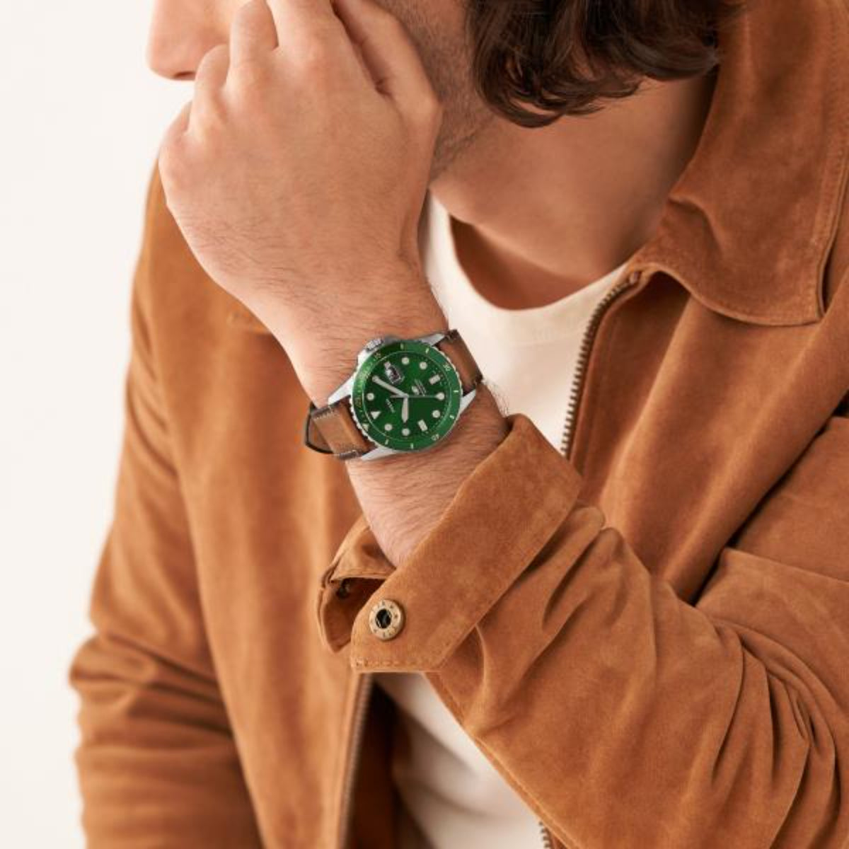 Men's green dial dive watch on wrist with brown leather strap