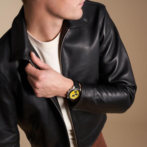 Men's chronograph watch on wrist with yellow dial and black silicone strap.
