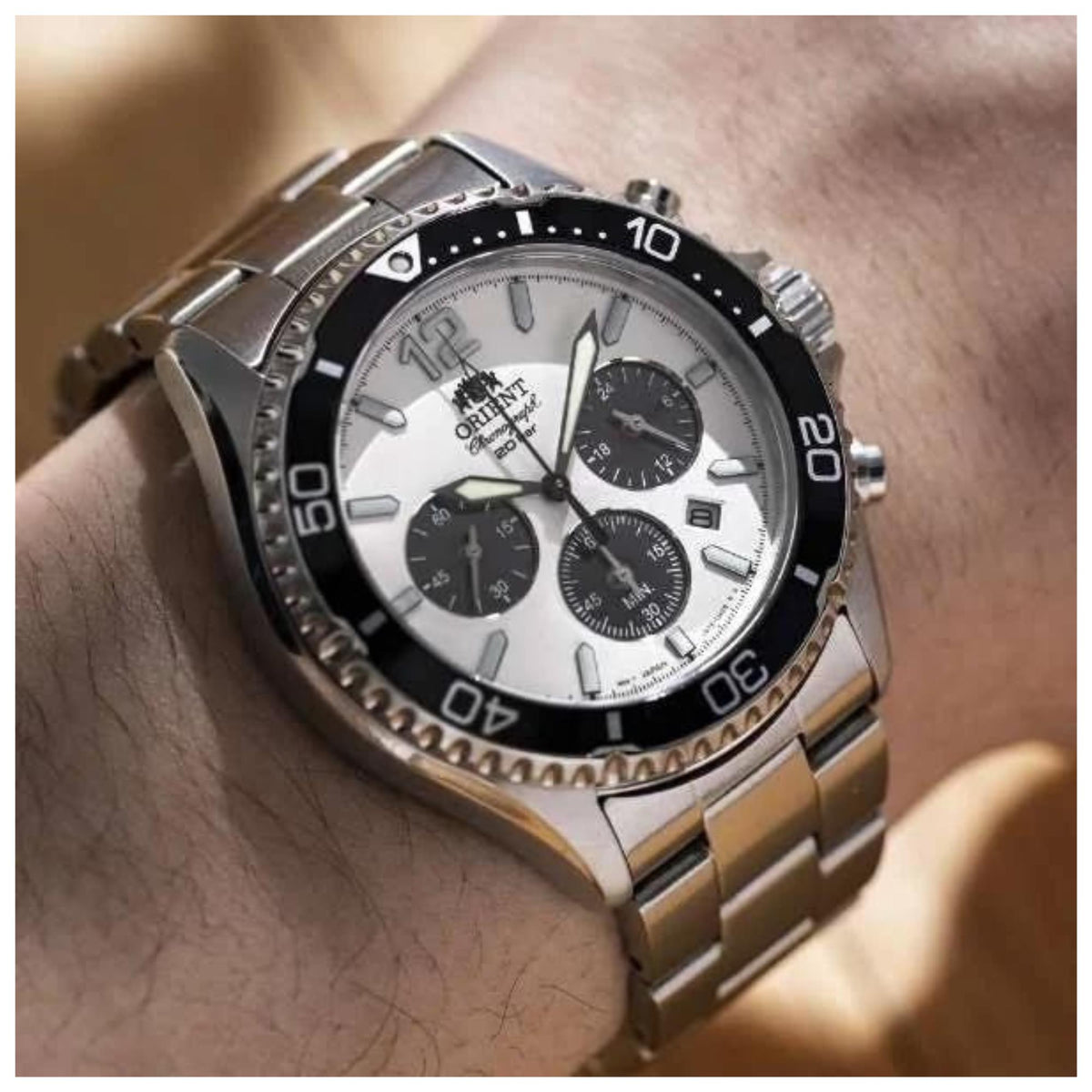 Mens steel chronograph wristwatch on wrist with white dial and black bezel